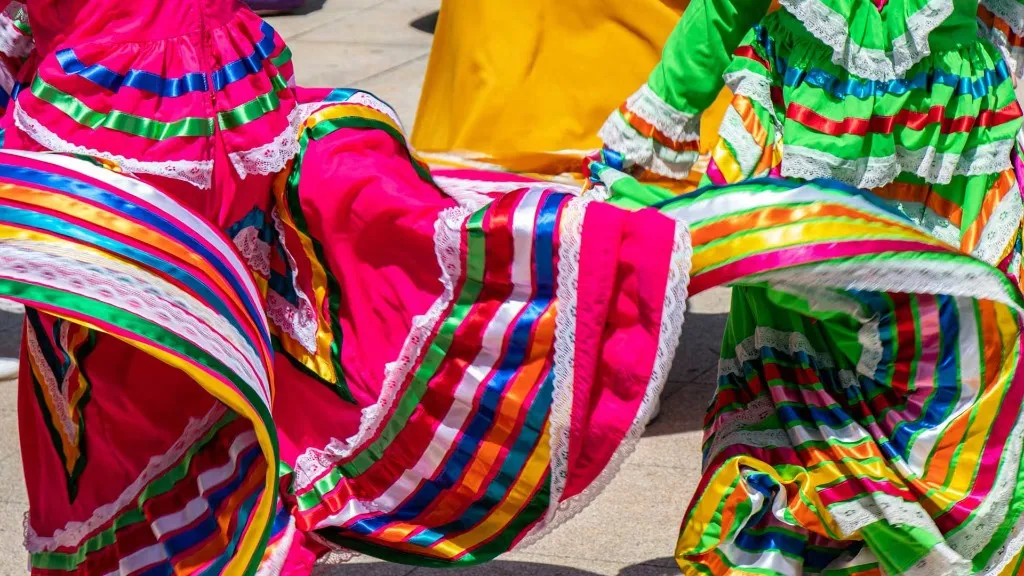 Traditional Mexican folklórico dancers in vivid pink and green skirts mid-spin